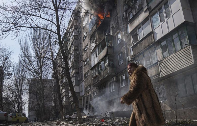 A woman walks past a burning apartment building after shelling in Mariupol, Ukraine, Sunday, March 13, 2022. (AP Photo/Evgeniy Maloletka) NYAG502 NYAG502
