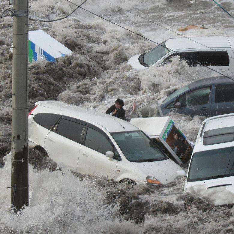 A newspaper reporter is swept away by surging water at the port city of Kamaishi in northeastern Japan. The region was struck by a massive earthquake that spawned the tsunami. The reporter survived. (The Associated Press, 2011)