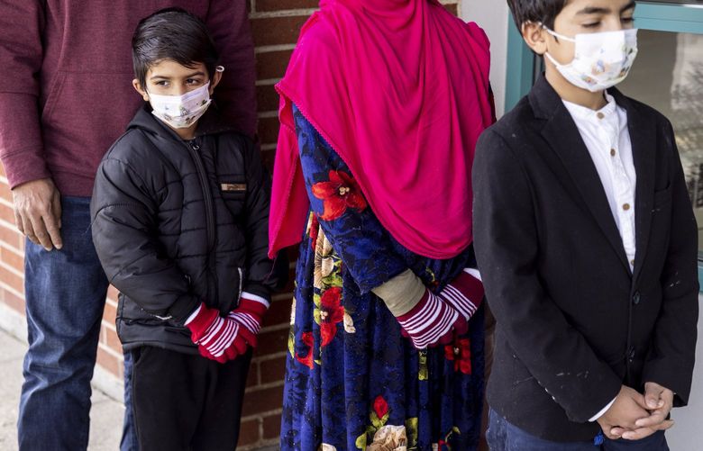 Mirwais, 7, left, and his family wait outside their new school, Southern Heights Elementary, where they will take a tour of the grounds and classes on Wednesday, Feb. 16, 2022 in Burien. 
The family are Afghan refugees and arrived in Seattle after the fall of Kabul. The boys and their sisters were set to begin school the next week.
