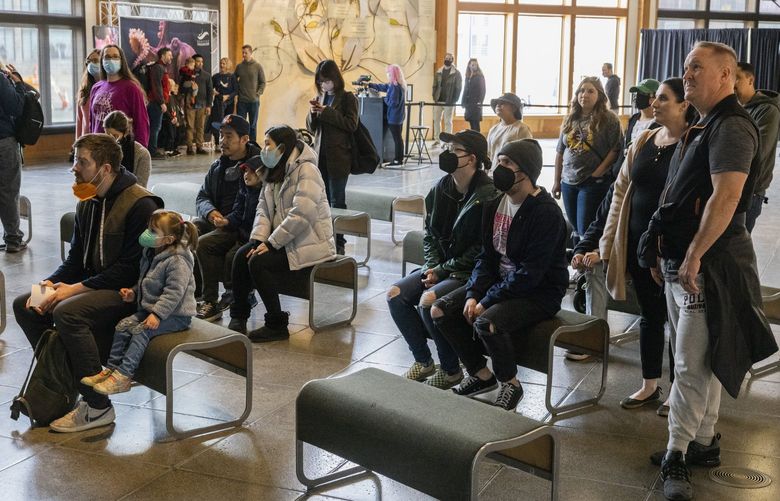 2022 年 3 月 12 日，戴口罩和未戴口罩的顾客在西雅图水族馆的“华盛顿水域之窗”展览上观看演示。从周六开始，华盛顿州取消了对大多数室内空间的戴口罩规定。