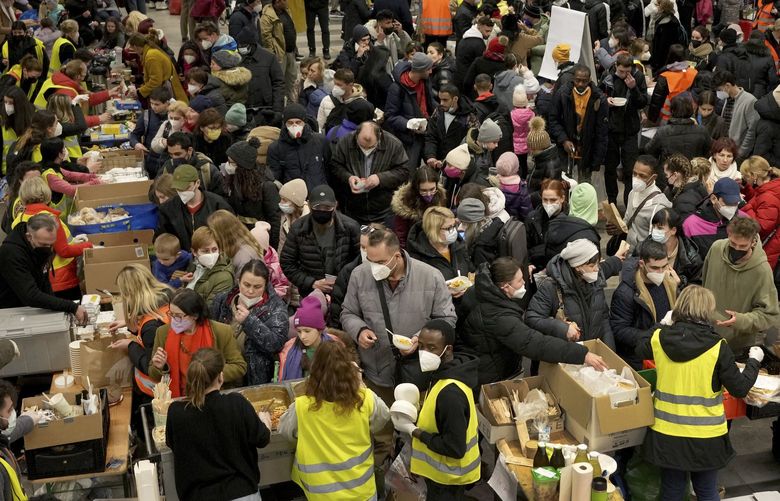 FILE – Ukrainian refugees queue for food in the welcome area after their arrival at the main train station in Berlin, Germany, March 8, 2022. The Ukraine war has turned the basement of Berlinâ€™s glass-and-steel main train station into a sprawling refugee town where a small army of volunteers in yellow and orange vests offer everything from shampoo to cell phone chargers to exhausted refugees. (AP Photo/Michael Sohn, File) MSC101 MSC101