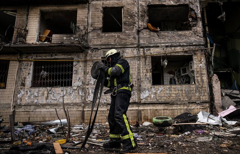 Emergency workers extinguish flames and help residents after their apartment building in the Obolon district of Kyiv, Ukraine, was struck by artillery shells on Monday, March 14, 2022. Two people were killed and nine wounded in the attack.  (Lynsey Addario/The New York Times) — NO SALES — XNYT93 XNYT93