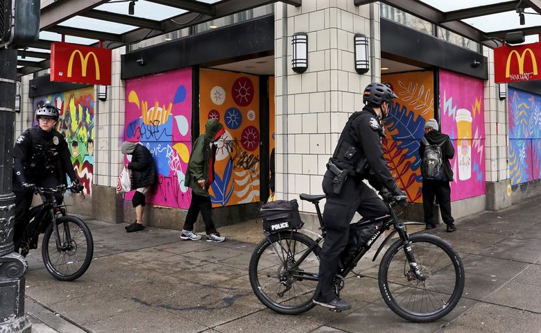 Bicycle police pass a boarded up McDonald’s in downtown Seattle. (Alan Berner / The Seattle Times)