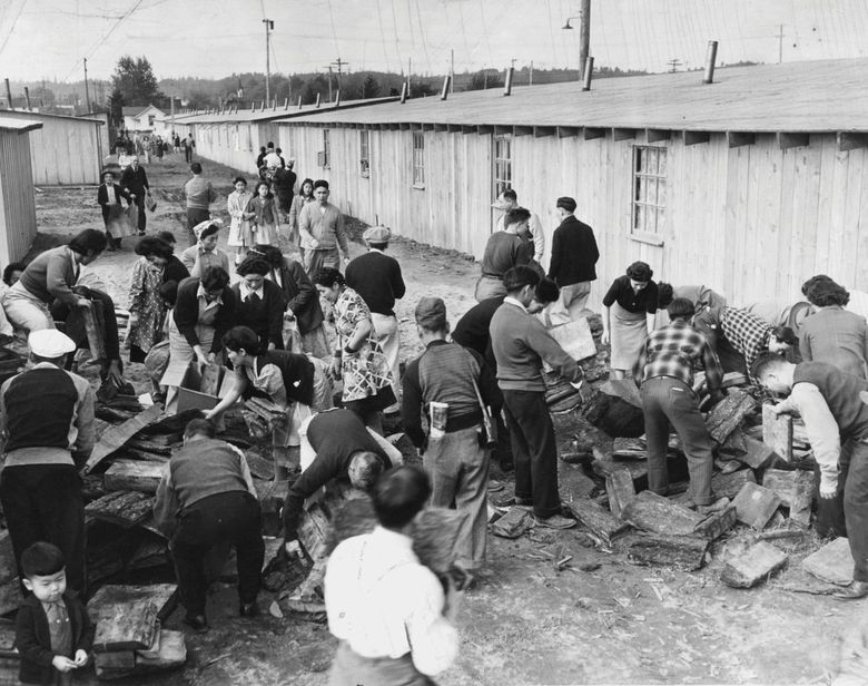 The incarceration camp at the Puyallup Fairgrounds in May of 1942. Since all the camp’s stoves were wood burners, every family developed a tremendous interest in wood deliveries made at street ends in trucks. Here, incarcerated people grab wood from a pile delivered by a volunteer wood detail. ( / The Seattle Times)