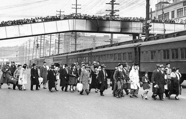 Seattle crowds jam an overhead walk to witness mass evacuation of Japanese from Bainbridge Island, Washington, March 30, 1942. Somewhat bewildered, but not protesting, some 225 Japanese men, women and children were taken by ferry, bus and train to California internment camps. Evacuation was carried out by the army. (AP Photo)