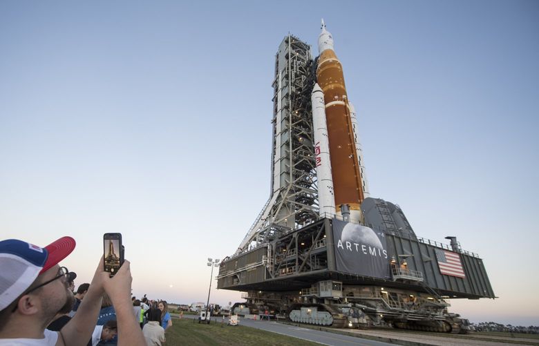 Invited guests and NASA employees take photos as NASA’s Space Launch System (SLS) rocket with the Orion spacecraft aboard is rolled out of High Bay 3 of the Vehicle Assembly Building for the first time, at the Kennedy Space Center in Cape Canaveral, Fla., Thursday, March 17, 2022. Ahead of NASA’s Artemis I flight test, the fully stacked and integrated SLS rocket and Orion spacecraft will undergo a wet dress rehearsal at Launch Complex 39B to verify systems and practice countdown procedures for the first launch. (Aubrey Gemignani/NASA via AP) 
