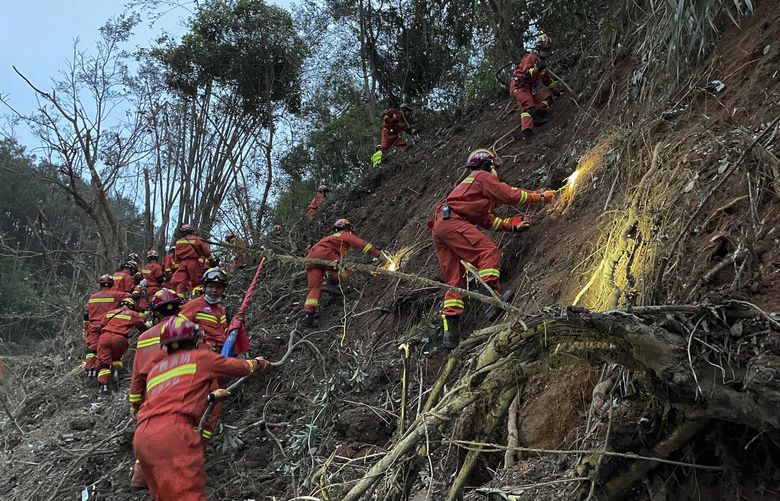 In this photo released by Xinhua News Agency, rescuers conduct search operations at the site of a plane crash in Tengxian County in southern China’s Guangxi Zhuang Autonomous Region, Tuesday, March 22, 2022. Mud-stained wallets. Bank cards. Official identity cards. Some of the personal effects of 132 lives presumed lost were lined up by rescue workers scouring a remote mountainside Tuesday for the wreckage of a China Eastern plane that one day earlier inexplicably fell from the sky and burst into a huge fireball. (Zhou Hua/Xinhua via AP) XIN803 XIN803
