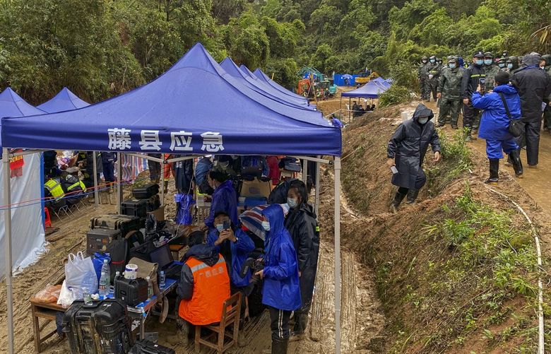 Emergency workers gather under a temporary command center on a mud-soaked hillside near the crashed site of the China Eastern Flight 5735, Thursday, March 24, 2022, in Wuzhou city, in southwestern China’s Guangxi province. The search area was expanded Thursday in a “blanket search” for the second black box from a China Eastern passenger plane that crashed in southern China with 132 people on board earlier this week, state media said. (AP Photo/Ng Han Guan) XAW107 XAW107