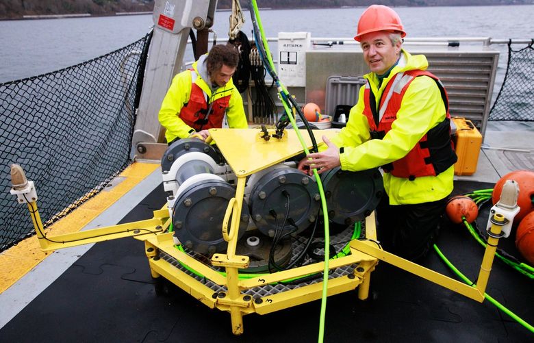SMRU Consulting’s managing director Jason Wood, front, and field engineer Sam Tabbutt work on the lander of a coastal acoustic buoy in Puget Sound on March 16. The device measures underwater noise and detects vocalizing marine mammals with underwater microphones. (Erika Schultz / The Seattle Times)