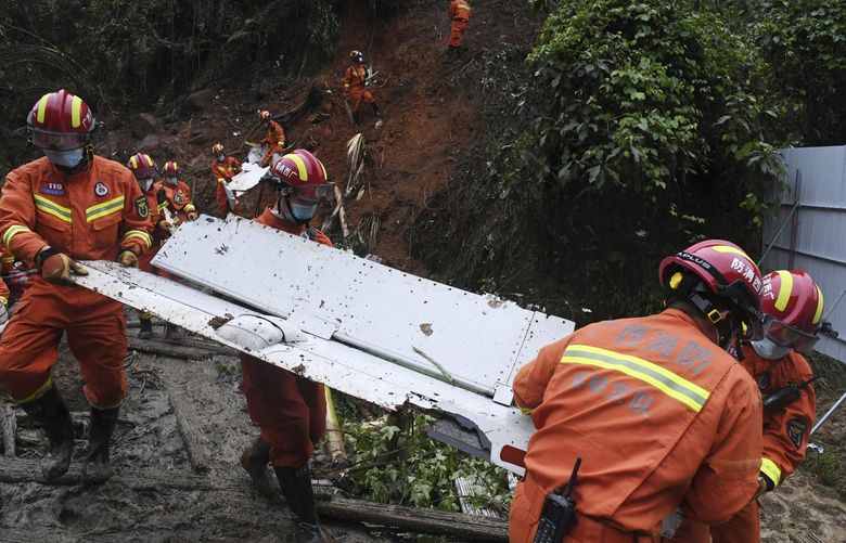 In this photo released by Xinhua News Agency, search and rescue workers carry pieces of debris which were recovered at the China Eastern flight crash site in Tengxian County in southern China’s Guangxi Zhuang Autonomous Region on Thursday, March 24, 2022. Hundreds of people in rain gear and rubber boots searched muddy, forested hills in southern China on Thursday for the second flight recorder from a jetliner that crashed with 132 people aboard. (Lu Boan/Xinhua via AP) XIN805 XIN805
