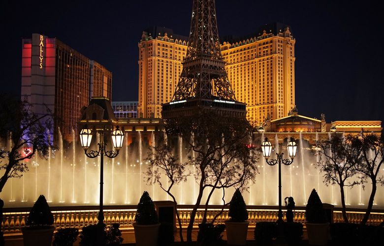 FILE – In this Nov. 19, 2020, file photo, a woman watches the fountains at the Bellagio hotel-casino along the Las Vegas Strip in Las Vegas. Gambling giant MGM Resorts International is joining the growing number of Las Vegas Strip casinos with state regulatory approval to open casino floors at 100% capacity and no person-to-person distancing requirement. The company said Wednesday, May 12, 2021, it got Nevada Gaming Control Board approval for the Bellagio, ARIA, MGM Grand, Mandalay Bay, Mirage, New York-New York, Luxor, Excalibur and Park MGM. (AP Photo/John Locher, File)