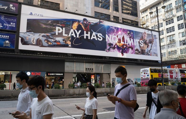 Pedestrians wearing protective mask walk past a billboard advertising the Sony Corp. PlayStation 5 game console in Hong Kong, China, on Thursday, Nov. 26, 2020. The newest video-game console from Sony Corp., alongside rival Microsoft Corp.’s updated Xbox, are arguably the hottest items this Black Friday as shoppers line up in person or swarm retailers’ websites hoping to snag one. Photographer: Roy Liu/Bloomberg
