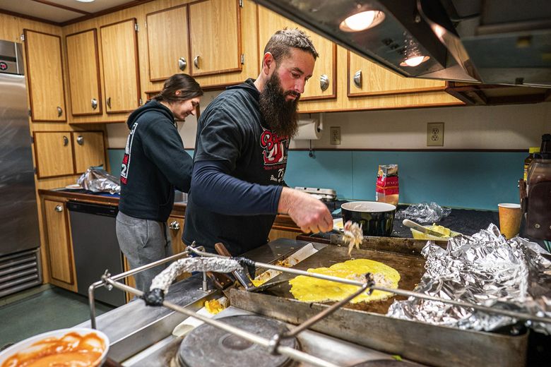 Stephen Jamieson makes crab omelets in the Pinnacle galley Jan. 24. Behind Jamieson is Madison Smotherman. (Loren Holmes / Anchorage Daily News) 
