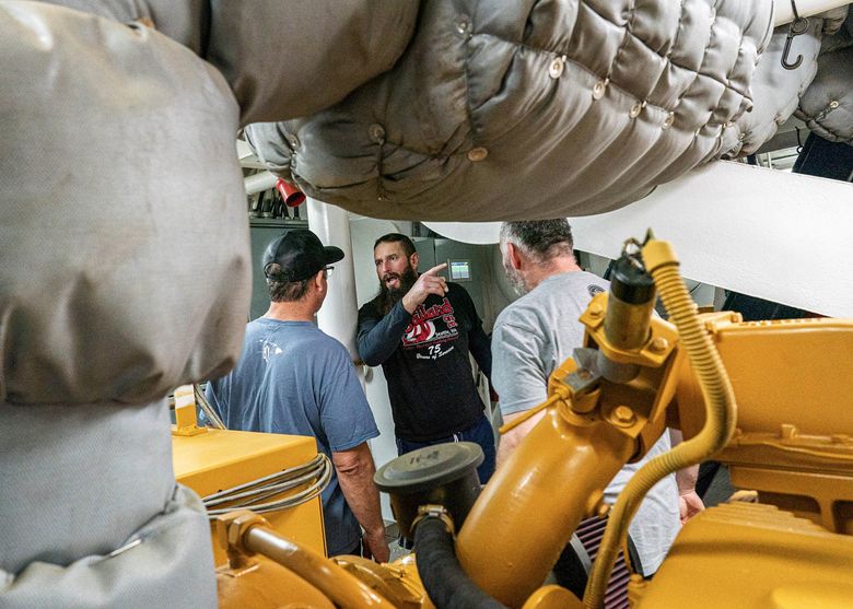 Crewman Stephen Jamieson, center, talks with Capt. Mark Casto, left, and engineer Mike Grant as they try to diagnose the cause of a generator malfunction on Jan. 24. (Loren Holmes / Anchorage Daily News) 