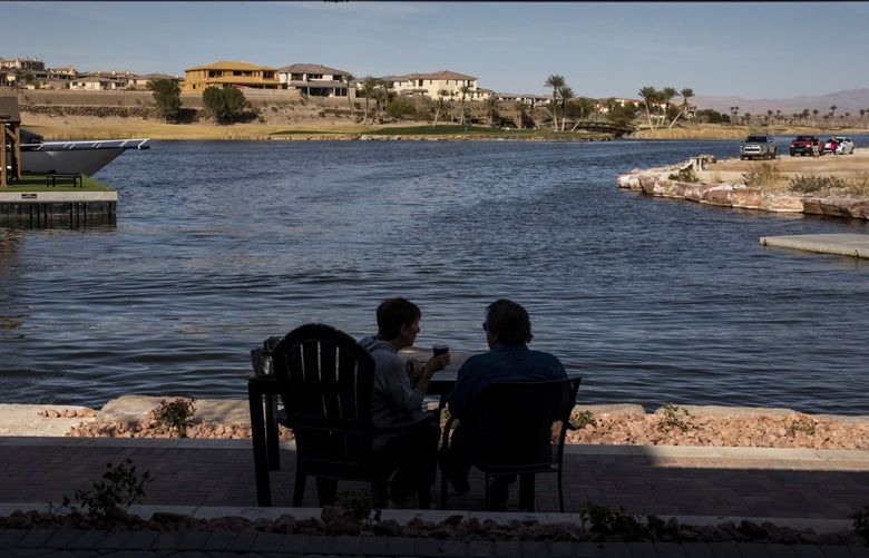 People sit by the water at The Village of the Lake Las Vegas residential resort community in Henderson, Nev., on Feb. 17, 2020.