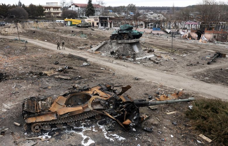 Local residents pass by a damaged Russian tank in the town of Trostyanets, east of capital Kyiv, Ukraine, Monday, March 28, 2022. The monument to Second World War is seen in background. (AP Photo/Efrem Lukatsky) NYAG510 NYAG510