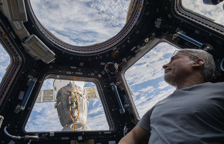 In this photo provided by NASA, U.S. astronaut and Expedition 66 Flight Engineer Mark Vande Hei peers at the Earth below from inside the seven-windowed cupola, the International Space Station’s window to the world on Feb. 4, 2022. The Soyuz MS-19 crew ship is docked to the Rassvet module in the background. Vande Hei has made it through nearly a year in space, but in March 2022 faces what could be his trickiest assignment yet: riding a Russian capsule back to Earth in the midst of deepening tensions between the countries. (Kayla Barron/NASA via AP) NY751 NY751