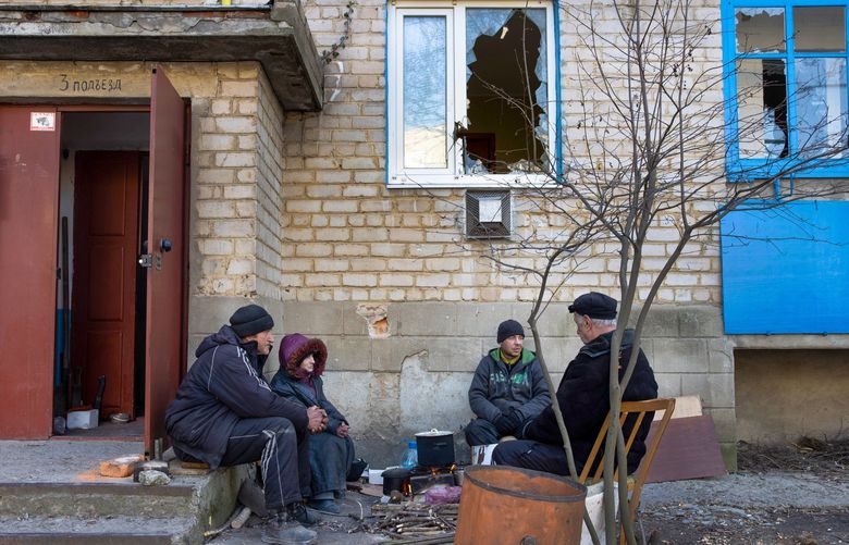 Residents warm food over a fire outside a damaged apartment building in Huliaipole, Ukraine, March 28, 2022. In the weeks since Russia began its invasion, more than 953 civilians have been killed, including at least 78 children, according to the United Nations high commissioner for human rights, who noted that the real toll was likely to be considerably higher. (Tyler Hicks/The New York Times) XNYT136