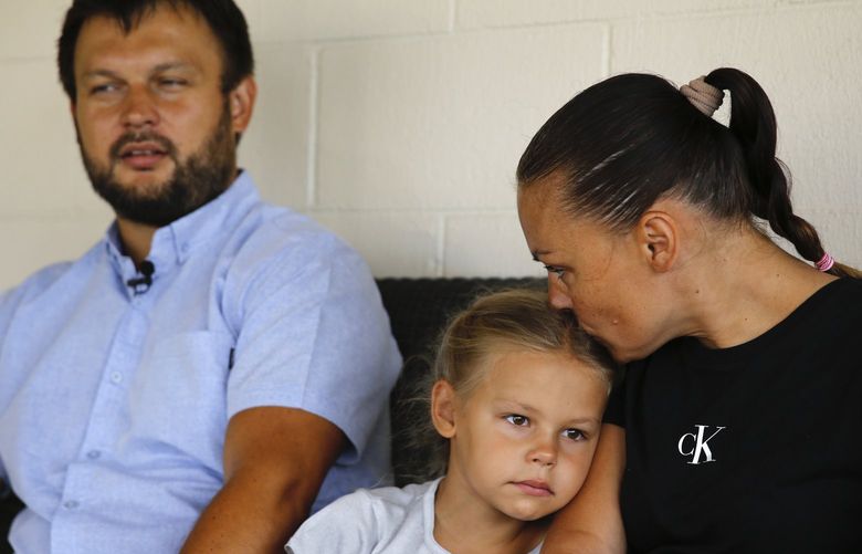 Vasyl Prishchak, left, is interviewed by The Associated Press as his wife, Marina, right, and daughter, Ksenia, 5, sit next to him at their temporary home in Kailua, Hawaii, Wednesday, March 23, 2022. The Prishchak family travelled to Hawaii for a long-awaited vacation on Feb. 16 and planned to return to Ukraine on March 7. But a week into their vacation, Russia invaded their country, leaving the family in shocked disbelief with no access to family, friends, money or their home. (AP Photo/Caleb Jones) HICJ101 HICJ101
