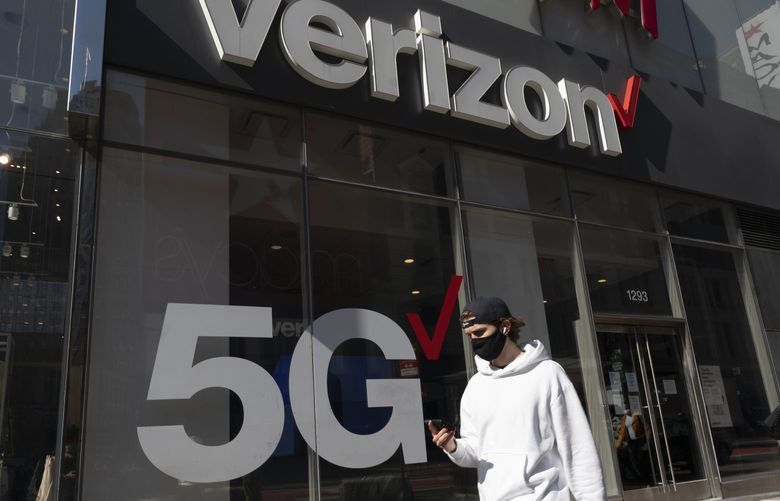 A man uses a mobile phone as he walks by a Verizon store, Monday, April 19, 2021, in New York. (AP Photo/Mark Lennihan) 
