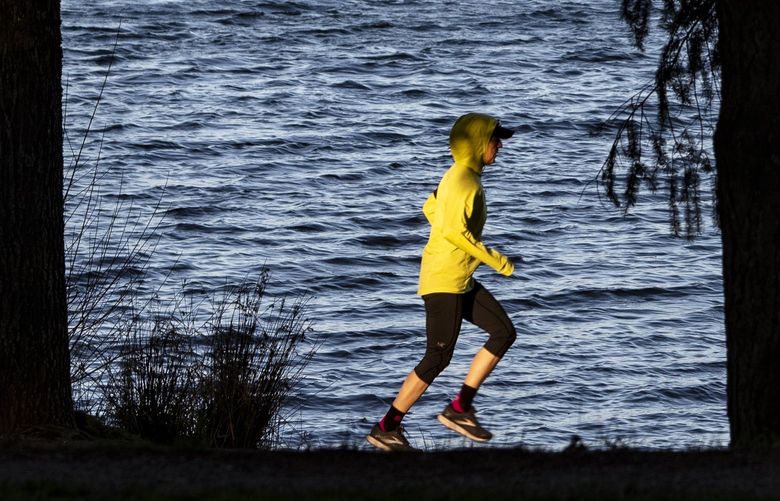 A runner at Green Lake is seen as the sun goes down, Wednesday, March 9, 2022 in Seattle. Daylight Saving Time begins Sunday as clocks are set ahead one hour. 219812