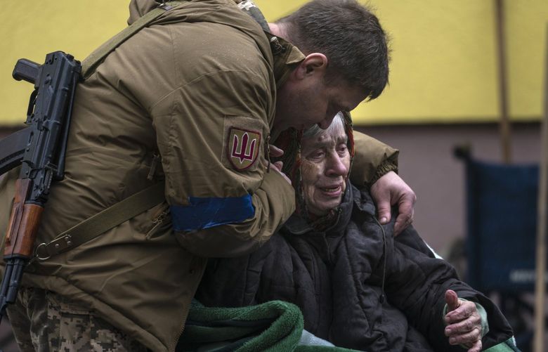 A soldier comforts Larysa Kolesnyk, 82, after being evacuated from Irpin, on the outskirts of Kyiv, Ukraine, Wednesday, March 30, 2022. (AP Photo/Rodrigo Abd) NYAG506 NYAG506