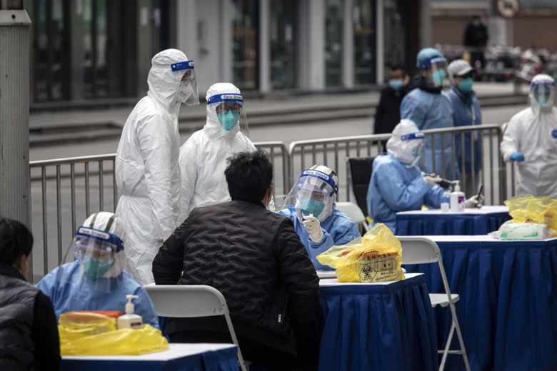 2022 年 3 月 10 日，医护人员在上海服装市场外进行新冠病毒检测。（彭博社照片，沉启来）。