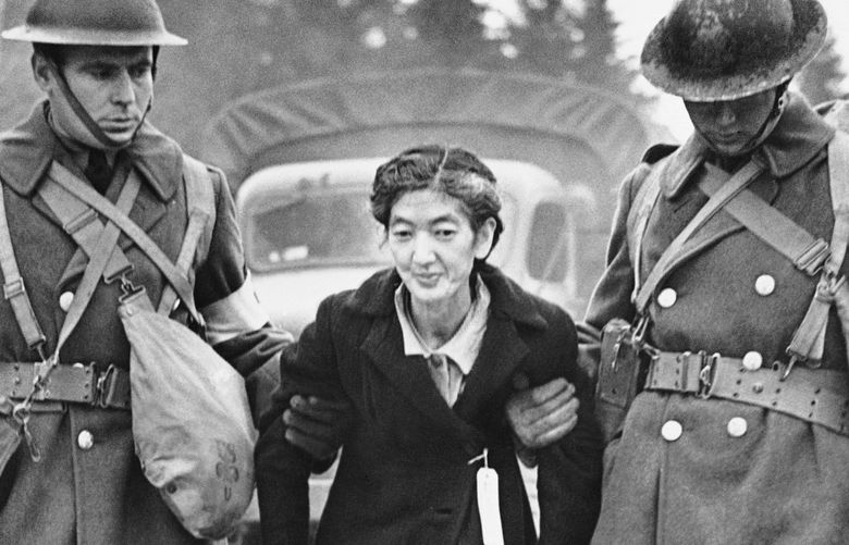 Army medical corps members assist a Bainbridge Island woman to the ferry during the mandatory evacuation of 227 people of Japanese ancestry living on Bainbridge Island on March 30, 1942. Credit: The Seattle Times Archives
Bill, here is the original caption that was attached to The Times file photo: FILE – In this April 1, 1942, file photo, U.S. Army medical corps members assist a Japanese woman in Seattle to the ferry at Bainbridge Island in Puget Sound after she collapsed during the evacuation of more than 300 Japanese from the island. The evacuees were taken by train to an inland internment site. (The Seattle Times via AP, File)