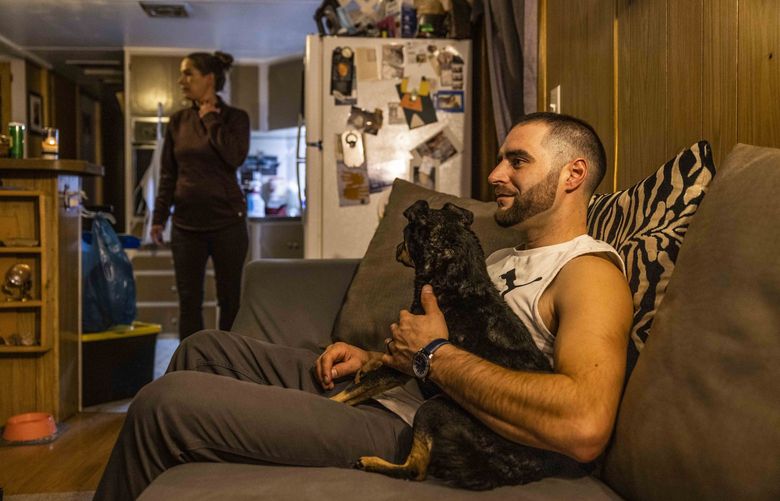 Michael Barajas, 33, hugs his dog Stella, a pug chihuahua mix, as he watches television, Feb. 2, 2022, as his fiancé Lindsay Garcia, 37, settles at their Aberdeen home after a shift at work. Barajas who says he used to use heroin, meth and pills says has been been using buprenorphine since July 2019. “It’s taken that craving away to want to continue to use that’s normally there. It’s help me not go through the withdrawals,” as he talks about how buprenorphine has changed his life.