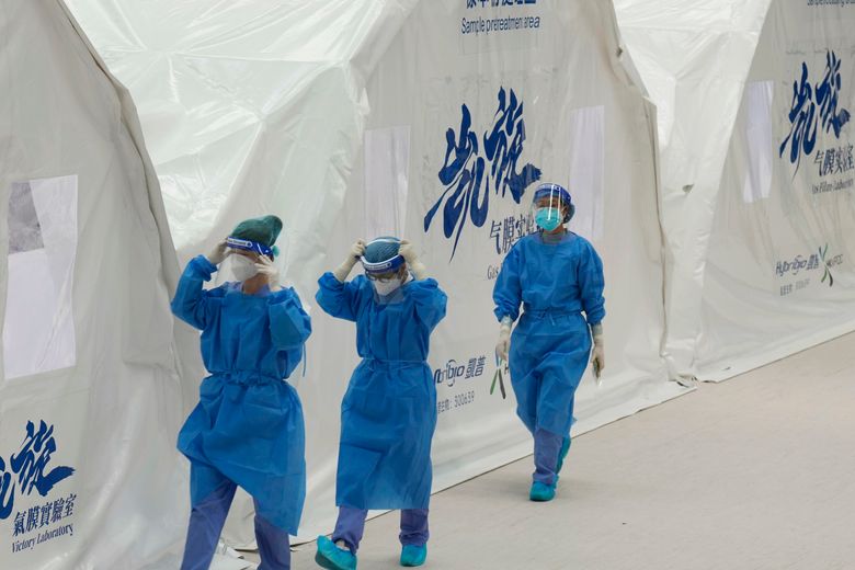 2022 年 3 月 1 日，星期二，身穿防护装备的中国大陆卫生工作者聚集在香港体育中心的冠状病毒充气移动检测实验室外。香港在充气移动实验室的帮助下提高了检测能力，因为该市每天处理数以万计的 COVID-19 病例。 （美联社照片/Vincent Yu）