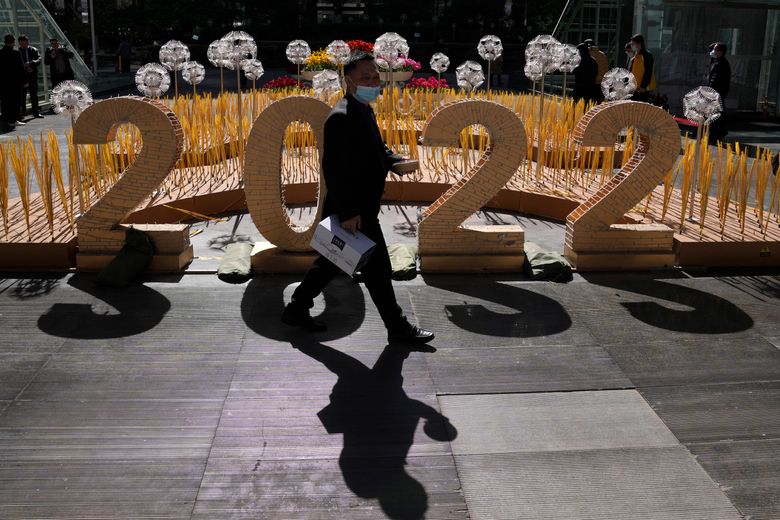 2022 年 3 月 7 日星期一，一名戴着口罩的男子走过北京一栋办公楼外的 2022 标志。 尽管中国采取了严厉的“零容忍”方法来应对疫情，但中国的 COVID-19 病例在广大国家出现了新的激增。 （美联社照片/吴汉冠）