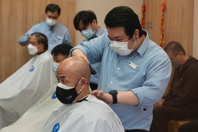 2022 年 3 月 10 日，星期四，香港暂时关闭后，戴着口罩的人们在沙龙理发。（美联社照片/Vincent Yu）