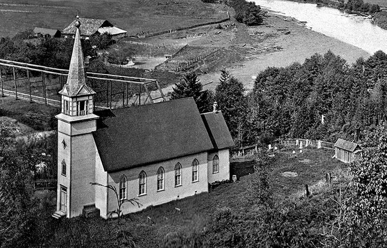 THEN: Like a Dutch Masters landscape painting, the Little White Church on the Hill anchors a pastoral scene. The Stillaguamish River curves just below, while the distant bluffs of Camano Island peep above the central horizon. The church’s steeple was added in 1904. Our best guess is that this photo was taken before 1910. Credit: Paul Dorpat Collection
