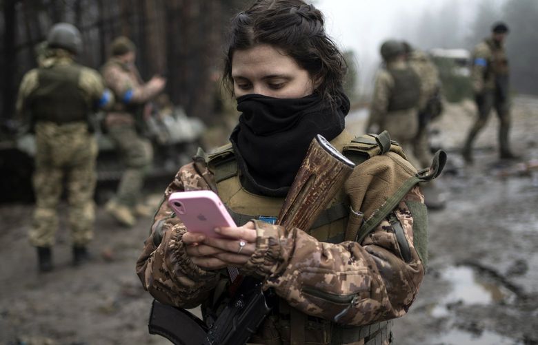 Ukrainian army soldier Dasha, 22, checks her phone after a military sweep to search for possible remnants of Russian troops after their withdrawal from villages in the outskirts of Kyiv, Ukraine, Friday, April 1, 2022. (AP Photo/Rodrigo Abd) ABD115 ABD115
