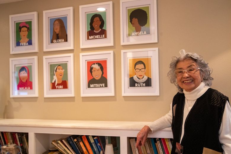 Mitsuye Yamada poses for a photo in front of a wall featuring an art piece of her and other inspirational women leaders at her home, Feb. 21, 2022 in Irvine, Calif. (Jennifer Buchanan / The Seattle Times)