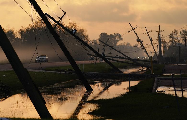 FILE – Downed power lines slump over a road in the aftermath of Hurricane Ida, Friday, Sept. 3, 2021, in Reserve, La. Weather disasters fueled by climate change now roll across the U.S. year-round, battering the nation’s aging electric grid. (AP Photo/Matt Slocum, File) CLI101 CLI101