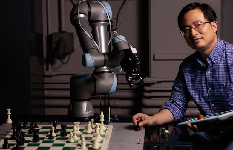 Associate professor of mechanical engineering Xu Chen is photographed with a robotic chess player at University of Washington’s Mechatronics, Automation and Control Systems (MACS) Laboratory Friday, April 1, 2022. 219740
