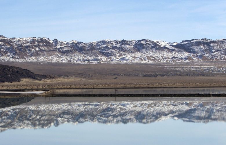 FILE – Mountains are reflected in an evaporation pond at the Silver Peak lithium mine in Esmeralda County, Nev. on Jan. 30, 2017. An Indiana couple missing for about a week has been found near the remote mountain area of southern Nevada, but the husband was dead and the wife was taken to a hospital, a sheriff’s official said. Ronnie Barker, 72, and Beverly Barker, 69, were found with their car late Tuesday, April 5, 2022, afternoon in the Silver Peak area of Esmeralda County, Mineral County Undersheriff Bill Ferguson said during a telephone interview. (Steve Marcus/Las Vegas Sun via AP, File) NVLVS301 NVLVS301