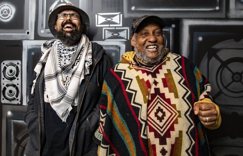 KEXP DJs Gabriel Teodros, left, and Riz Rollins share a good time together as their portrait is taken Wednesday, April 6, 2022 in Seattle. The station has come a long way since starting as KCMU 50 years ago. 220020