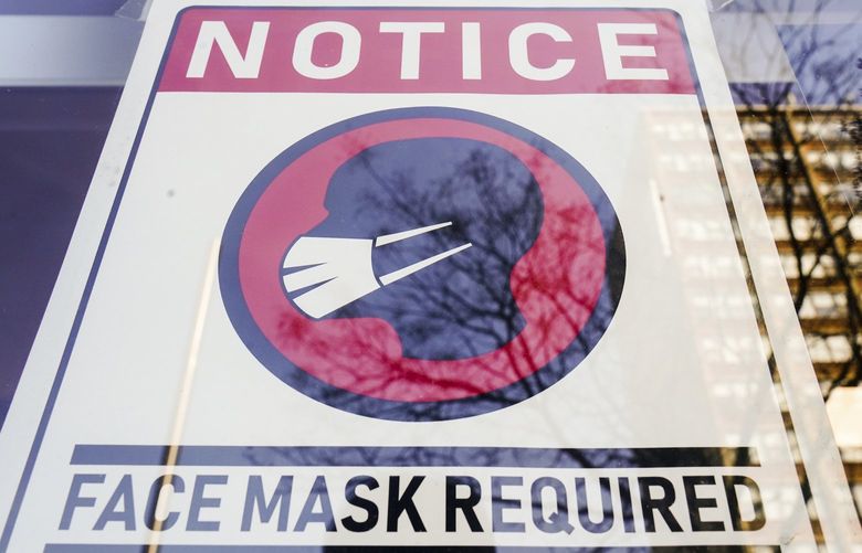 FILE – A sign requiring masks as a precaution against the spread of the coronavirus on a store front in Philadelphia, is seen Feb. 16, 2022. Philadelphia is reinstating its indoor mask mandate after reporting a sharp increase in coronavirus infections, Dr. Cheryl Bettigole, the city’s top health official, announced Monday, April 11, 2022. Confirmed COVID-19 cases have risen more than 50% in 10 days, the threshold at which the city’s guidelines call for people to wear masks indoors. (AP Photo/Matt Rourke, File) PAKS201 PAKS201