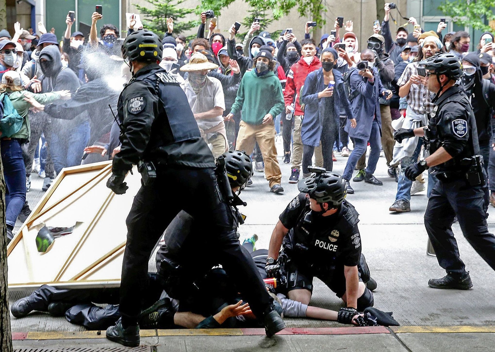 A Seattle police officer pepper-sprays protesters in downtown Seattle while another makes an arrest