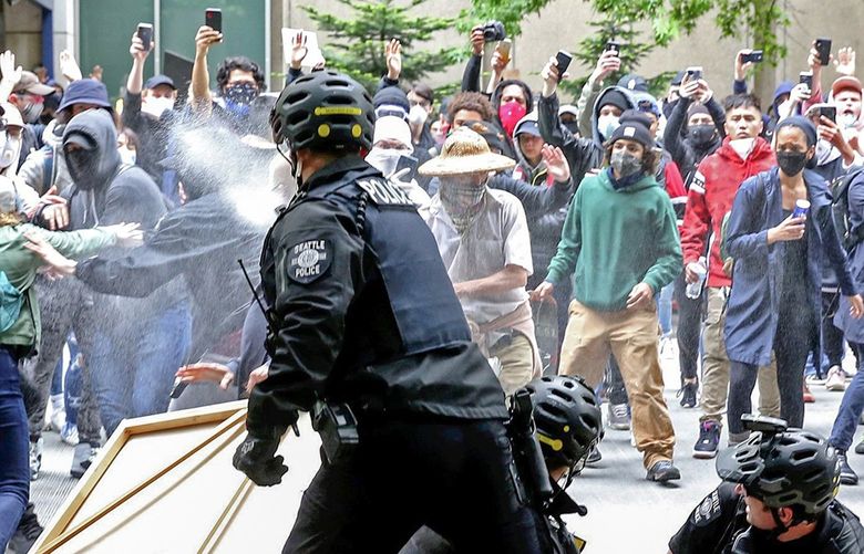 Protesters surrounding police making an arrest are pepper sprayed in downtown Seattle Sunday afternoon, May 31, 2020, as protests continue over the death of George Floyd in Minneapolis. A heavy burst of flashbangs started  after this moment. 214108 214108