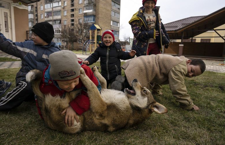 FILE – Children play with a dog in Bucha, on the outskirts of Kyiv, Ukraine, Friday, April 8, 2022. Local authorities told The Associated Press that at least 16 children were among the hundreds of people killed in Bucha. (AP Photo/Rodrigo Abd, File) NYAG904 NYAG904