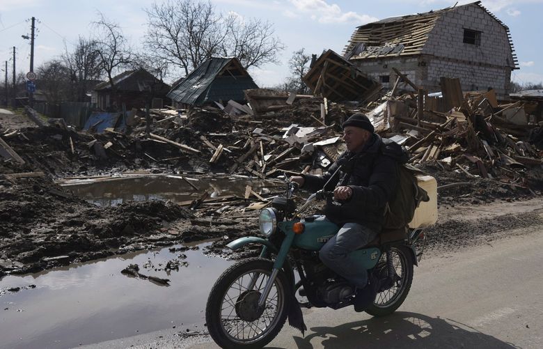 A man rides a motorbike past a house damaged by shelling in Chernihiv, Ukraine, Thursday, April 7, 2022. Ukraine is telling residents of its industrial heartland to leave while they still can after Russian forces withdrew from the shattered outskirts of Kyiv to regroup for an offensive in the country’s east. (AP Photo/Evgeniy Maloletka) XB139 XB139