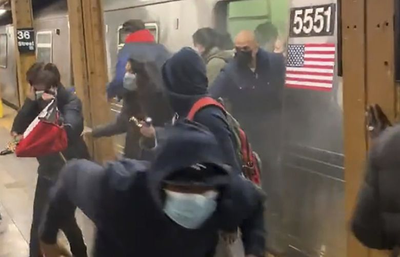 In this photo from social media video, passengers run from a subway car in a station in the Brooklyn borough of New York, Tuesday, April 12, 2022. A gunman filled a rush-hour subway train with smoke and shot multiple people Tuesday, leaving wounded commuters bleeding on a Brooklyn platform as others ran screaming, authorities said. Police were still searching for the suspect. (Will B Wylde via AP) NYRD220 NYRD220