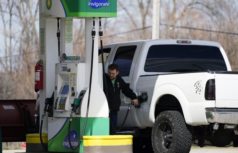 A man fills up his gas tank as he checks gas price at a gas station in Rolling Meadows, Ill., Friday, April 1, 2022. Analysts say the price of crude oil dropped below $100 million Friday for the first time since Feb. 28 following the president’s announcement of plans to release 180 million barrels of crude oil from the Strategic Petroleum Reserve over six months. (AP Photo/Nam Y. Huh) ILNH509 ILNH509