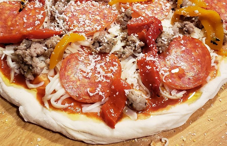 Providence Cicero’s husband, David, prepares a pizza for the oven. He makes his own dough and tops it with a wide variety of ingredients. Credit: Providence Cicero