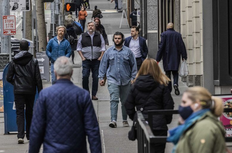 2 月，一群蒙面和未蒙面的行人在西雅图市中心散步。 （丹尼尔·金/西雅图时报）