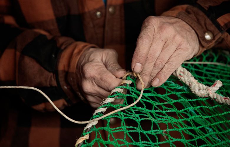 Lou Jones repairs slinky pots used to fish black cod at Fisherman’s Terminal in Seattle Wednesday, April 6, 2022. Jones said the Mystery Maid fishing boat crew would be departing to fish black cod and halibut on the Central Gulf of Alaska just after Easter. 
LO 220069