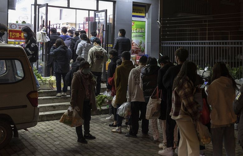 Residents wearing face masks to help protect from the coronavirus line up outside a supermarket at night to buy groceries on Sunday, March 27, 2022, in Shanghai, China. China began locking down most of its largest city of Shanghai on Monday as part of its strict COVID-19 strategy, amid questions over the policy’s economic toll on the country. (AP Photo) XBEJ101 XBEJ101